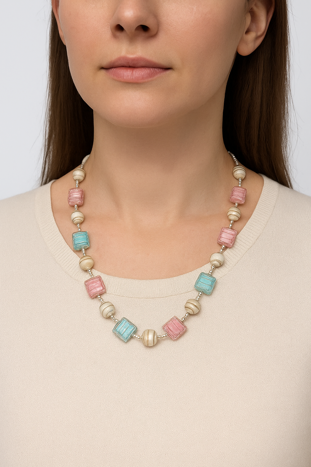 Necklace with colorful beads worn by a person on a plain background