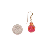 a pair of earrings with a coin in the background