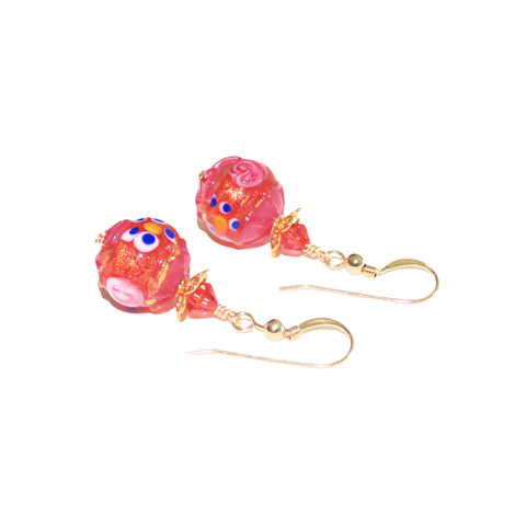 a pair of earrings with pink beads and gold hooks
