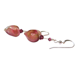 a pair of pink glass beads hanging from a hook