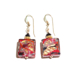 a pair of red and gold earrings on a white background