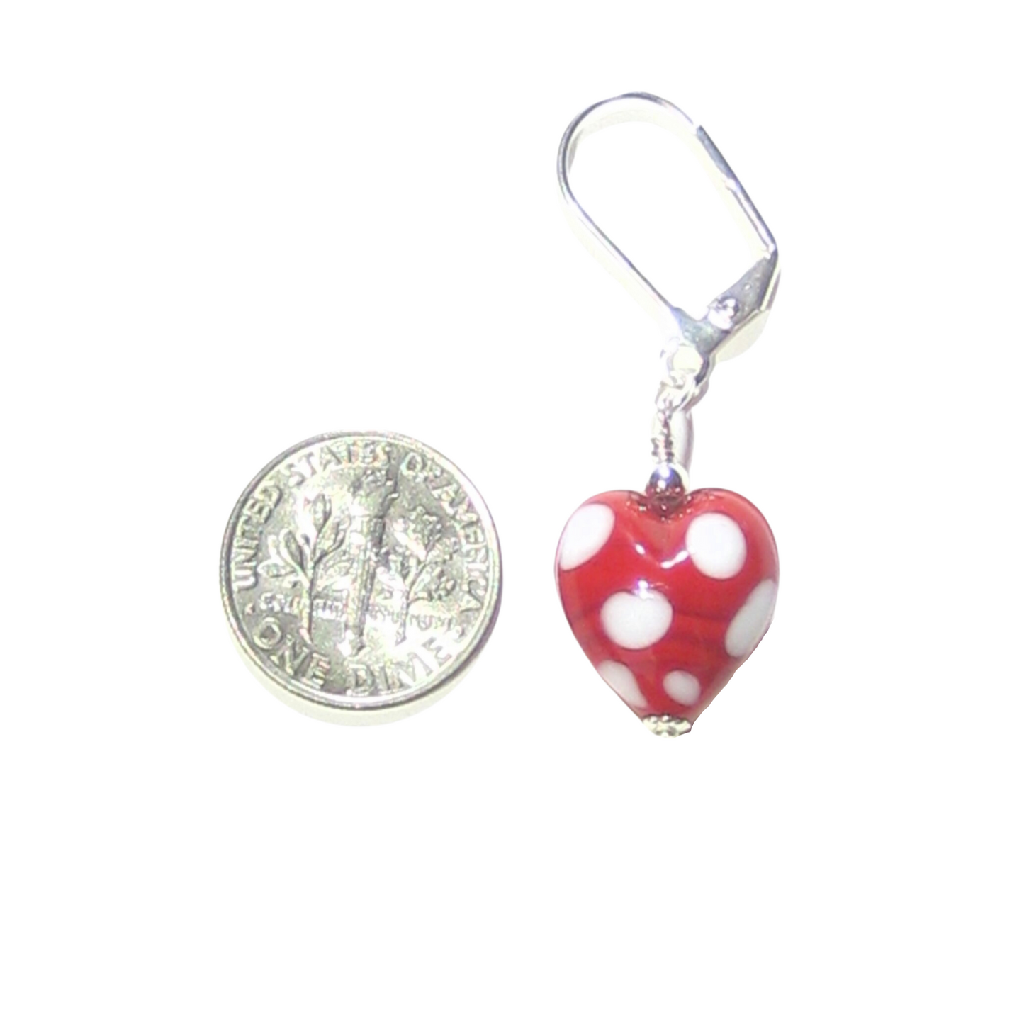 Red heart-shaped earring with white polka dots next to a dime for scale on a white background