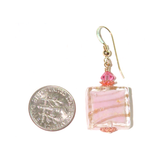 a pair of earrings with a pink cake on it