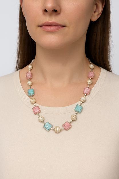 Necklace with colorful beads worn by a person on a plain background
