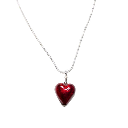Red heart-shaped pendant on a silver chain against a white background
