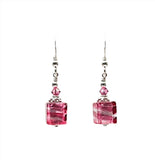 a pair of earrings with pink stones hanging from them