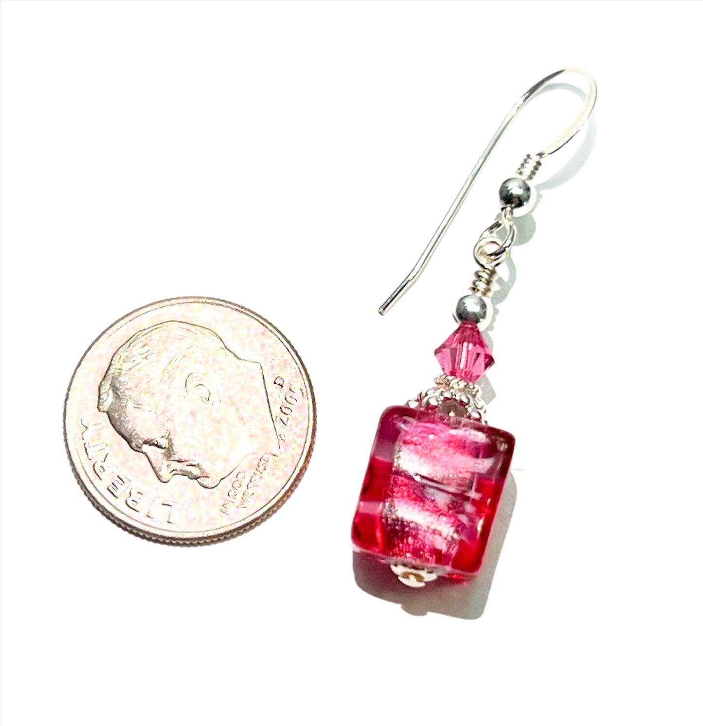 a penny and a pair of earrings on a white surface