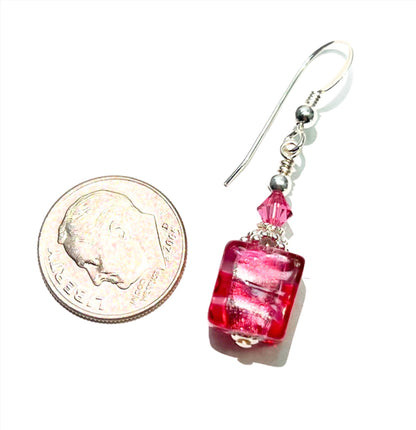 a penny and a pair of earrings on a white surface