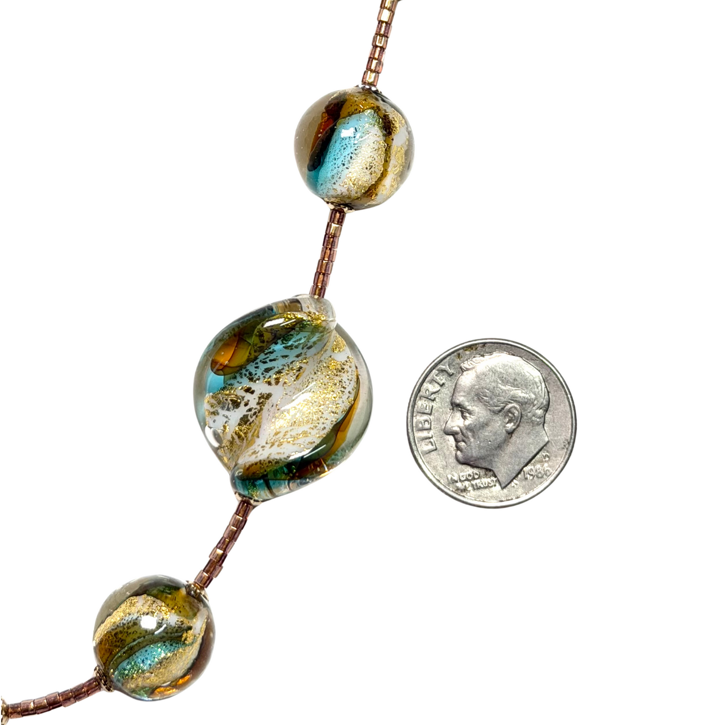 Three large beads with a dime for scale on a white background