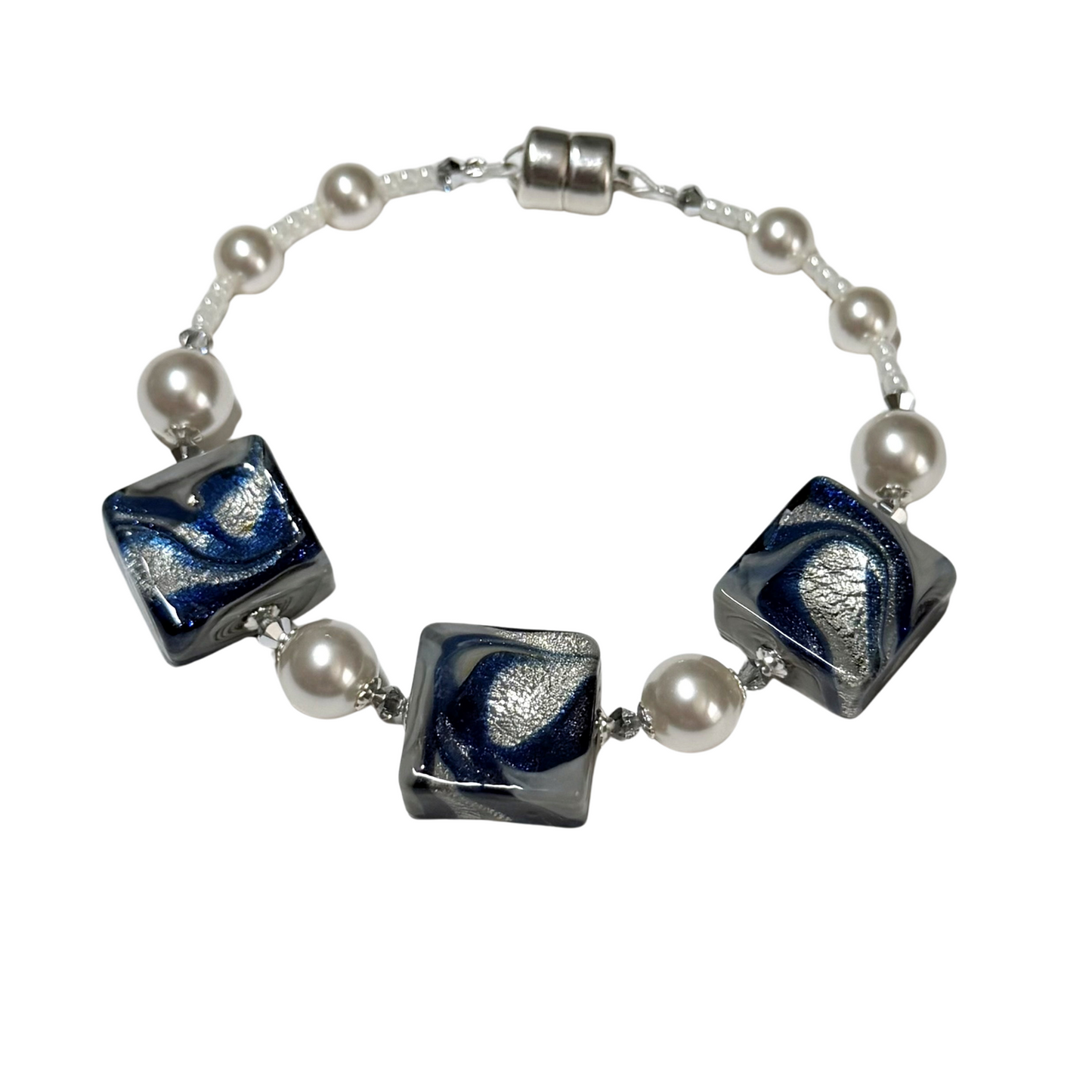 A beaded bracelet featuring three square glass beads with a blue and silver swirl pattern, separated by white faux pearls on a silver chain with a silver clasp.