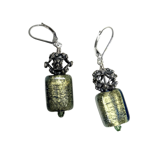 A pair of handmade glass drop earrings featuring textured olive green and gold lampwork beads, accented with dark oxidized filigree and silver leverback hooks, shown against a plain white background.
