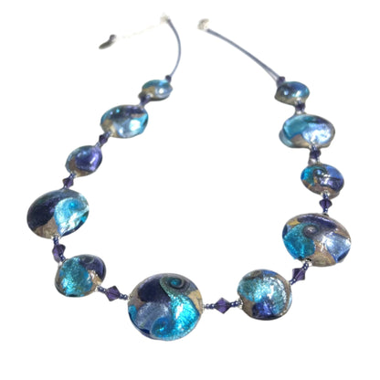 A Murano glass necklace with a combination of blue, purple, and tan colors, featuring sterling silver accents and a silver clasp.