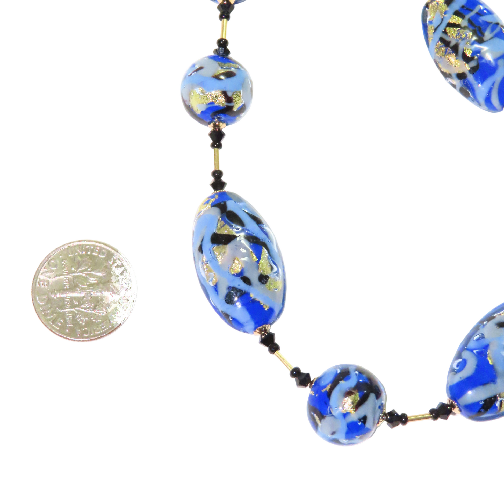 Necklace with blue and gold beads next to a coin for scale on a white background