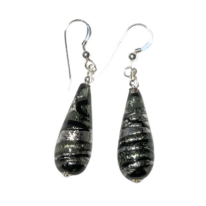 A pair of long silver earrings with a teardrop design and swirl patterns, featuring sterling silver findings.