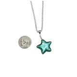 a small green glass star pendant next to a coin