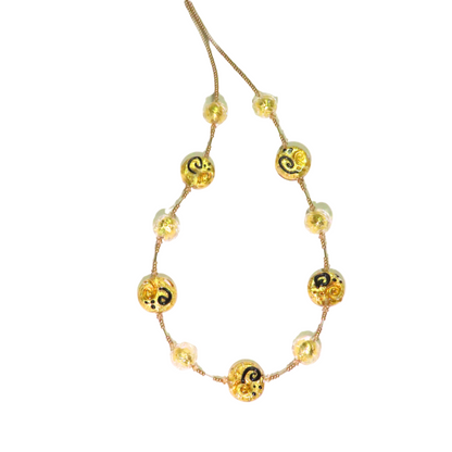 A gold Murano glass Miro coin necklace with abstract patterns and a gold filled clasp, displayed against a white background.
