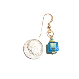 a pair of earrings with a coin hanging from it