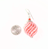 a penny sitting next to a pair of blown glass earrings