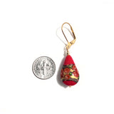 a red and gold pendant with a coin on a white background